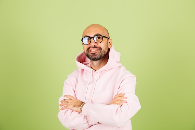 Free Photo young caucasian man in pink hoodie isolated, happy face smiling wearing glasses with crossed hands