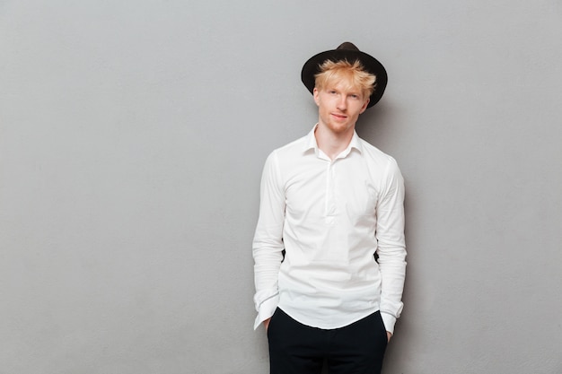 Young caucasian man standing isolated over grey wall