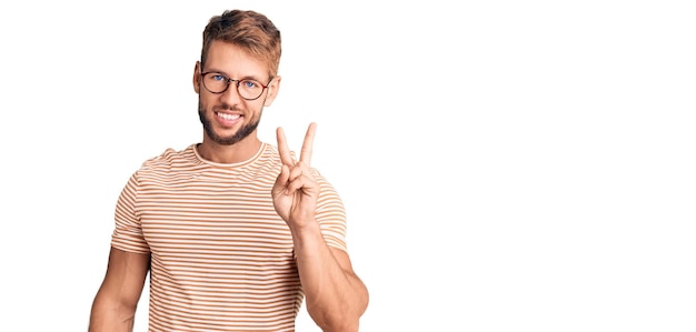 Young caucasian man wearing casual clothes and glasses showing and pointing up with fingers number two while smiling confident and happy.