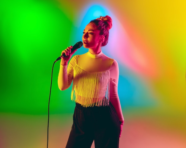 Free Photo young caucasian musician playing, singing on gradient space in neon light. concept of music, hobby, festival