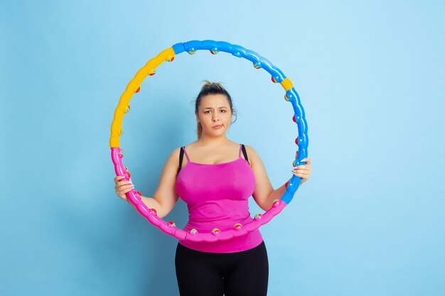 Young caucasian plus size female model's training on blue background