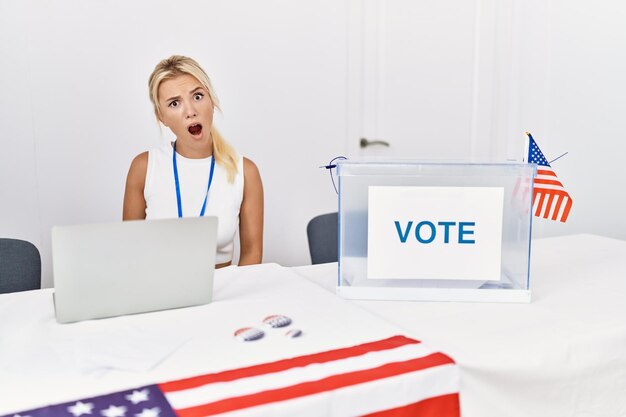 Young caucasian woman at america political campaign election in shock face looking skeptical and sarcastic surprised with open mouth