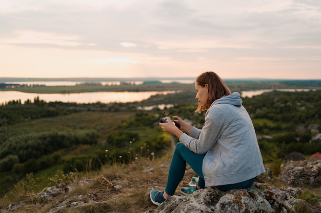 Free Photo young caucasian woman navigating a flying drone with remote control