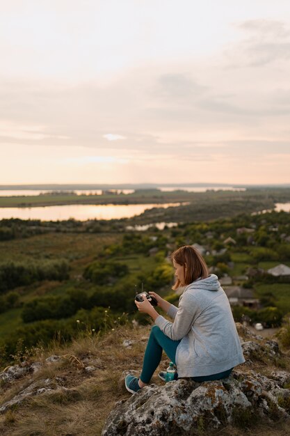 Young Caucasian woman navigating a flying drone with remote control