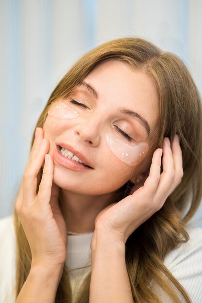 A young caucasian woman posing with patches under her eyes Skin care theme Vertical view