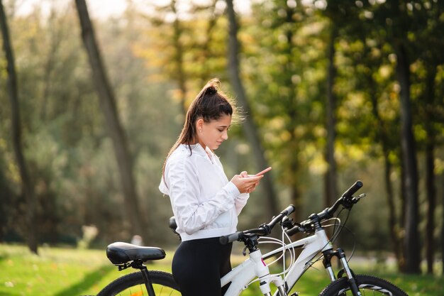 Young Caucasian woman resting in a park, uses a mobile phone.