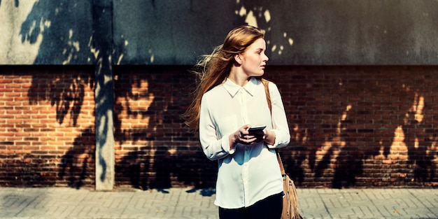 young caucasian woman standing using mobile phone outdoors