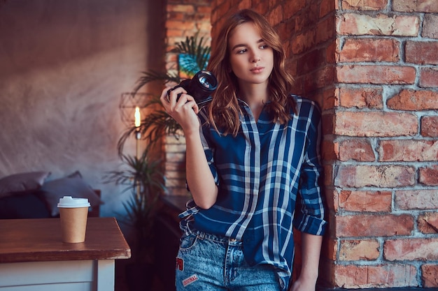 Young charming girl photographer stands in a room with a loft in