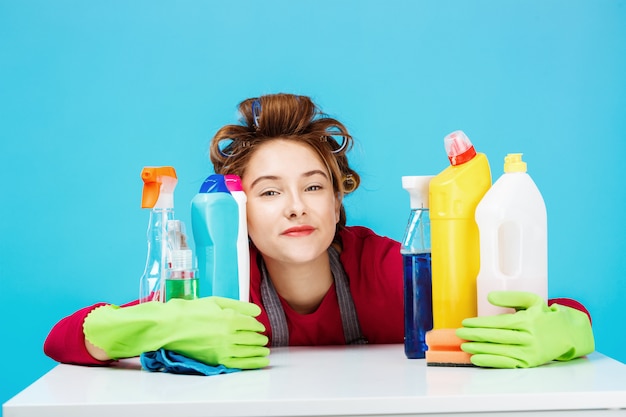 Young cheerful housewife and daily routine on blue wall