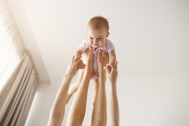 Free Photo young cheerful mother playing with her newborn baby lying on bed at home