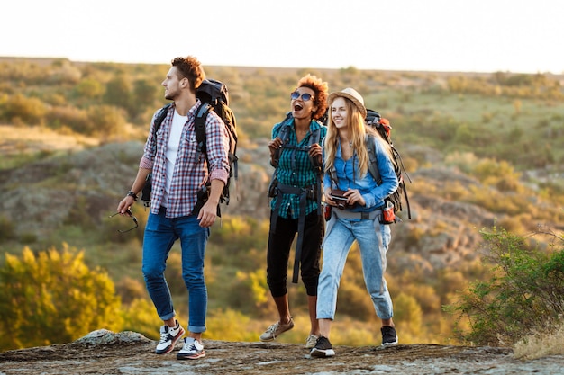 Young cheerful travelers with backpacks smiling, walking in canyon