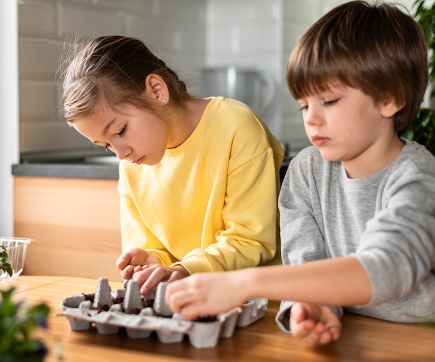 Free photo young children at home planting seeds