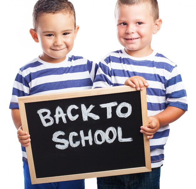 Free photo young children smiling with a blackboard with the message 