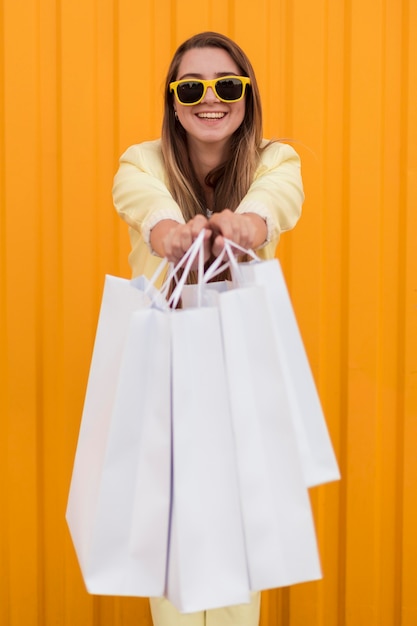 Young client wearing yellow clothes showing her shopping bags