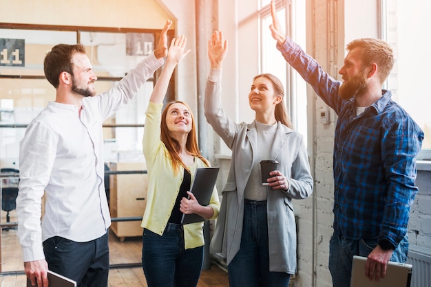 Free photo young colleagues giving high five to each other