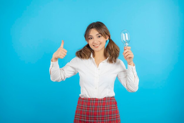 Young college girl holding light and gesturing thumb up. High quality photo