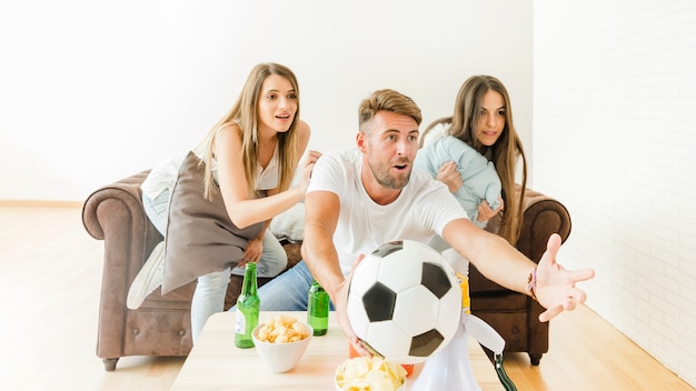 Young company watching football at sofa