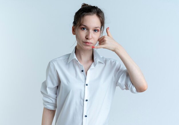 Young confident blonde russian girl gestures phone hand sign isolated on white space with copy space