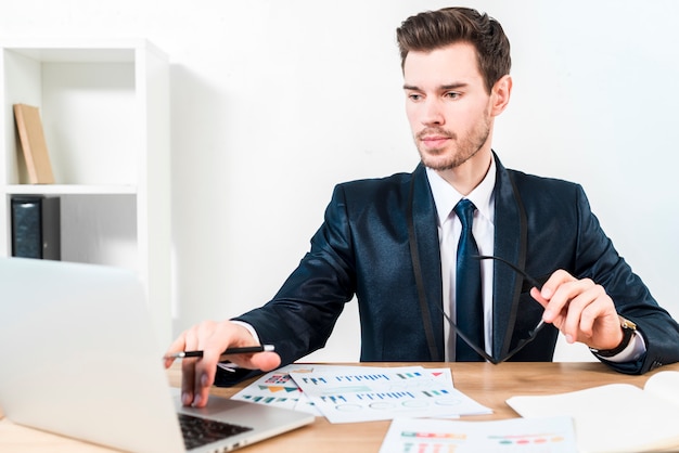 Young confident businessman using the laptop at workplace in the office