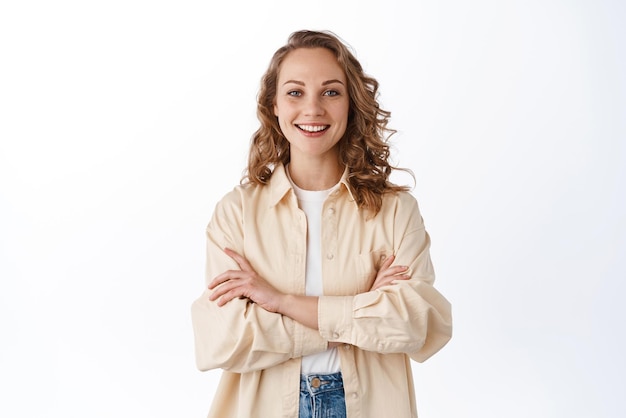 Free photo young confident woman with blond curly hair cross arms on chest and look determined smiling selfassured standing over white background copy space