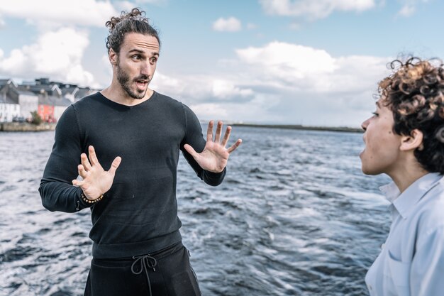 Young couple arguing expressively with the unfocused  sea