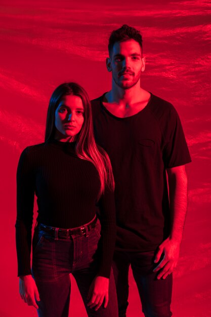 Young couple in black standing on red background 