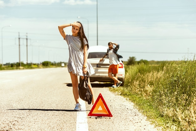 The young couple broke down the car while traveling on the way to rest.