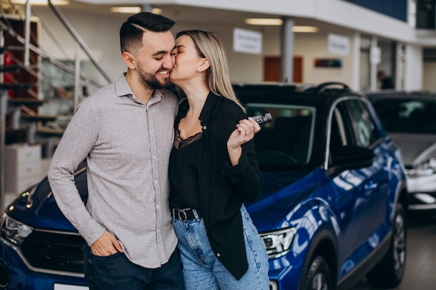 Young couple choosing a car in a car show room