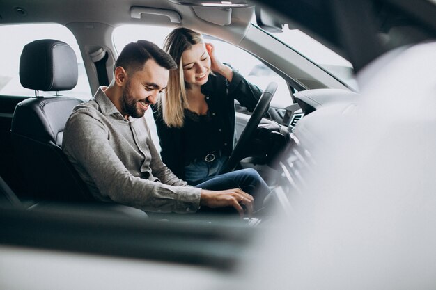 Young couple choosing a car in a car show room