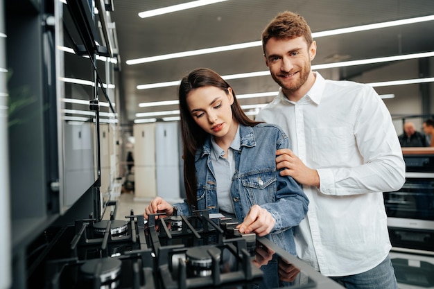 Free photo young couple choosing new gas stove in home appliances store