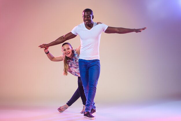 Young couple dances social Caribbean Salsa, studio shot