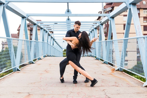 Free photo young couple dancing tango over the bridge