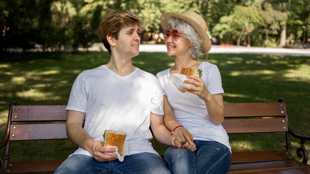 Young couple eating burgers in the park