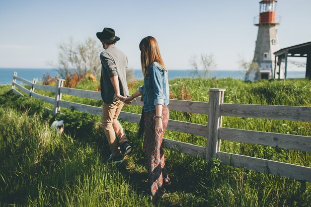 Young couple hipster indie style in love walking in countryside, holding hands