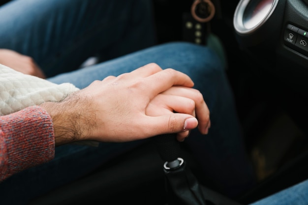 Free Photo young couple holding hands in car