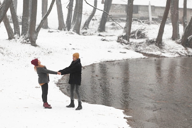 Free photo young couple holding their hands next to a river