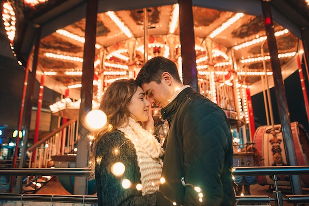 Young couple kissing and hugging outdoor in night street at christmas time