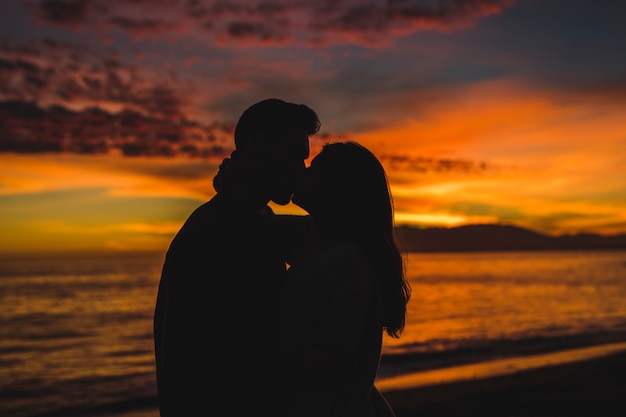 Young couple kissing on sea shore in evening 