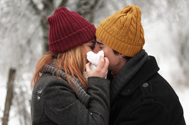 Free photo young couple kissing in winter season medium shot