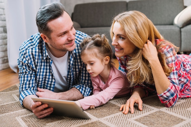 Free photo young couple looking at each other while daughter using digital tablet