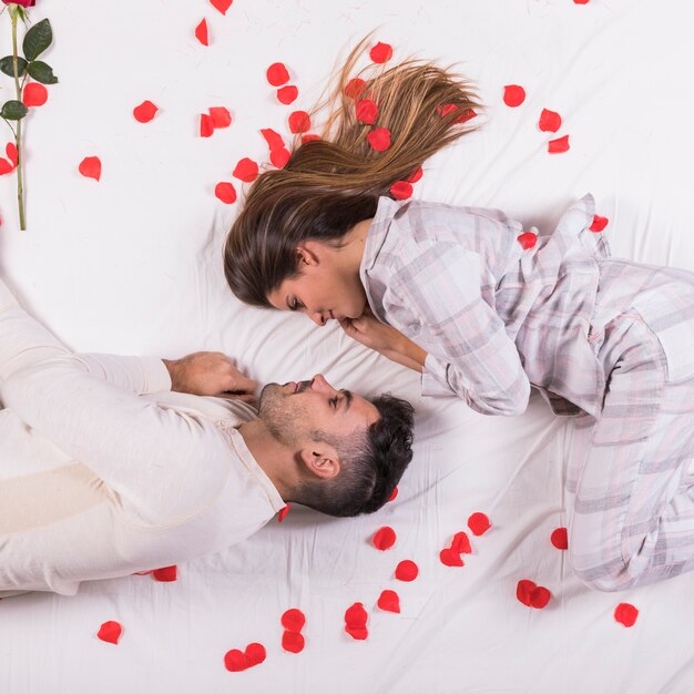 Young couple lying in bed with rose petals 