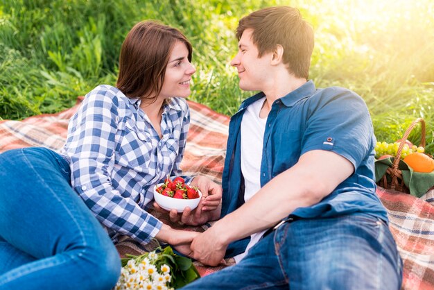 Free photo young couple lying on blanket and holding hands