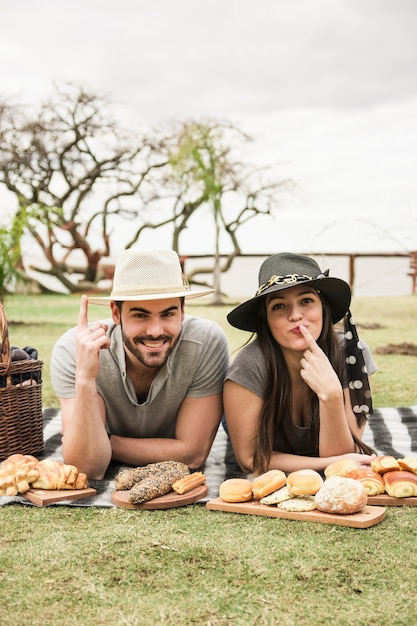 Young couple lying on blanket pointing finger at picnic in the park