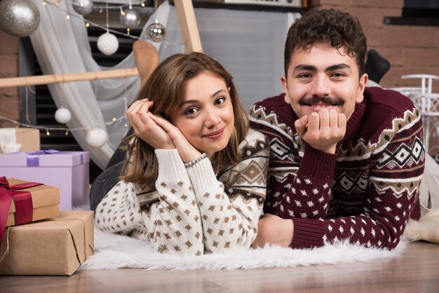 Young couple lying down on the floor in Christmas interior.