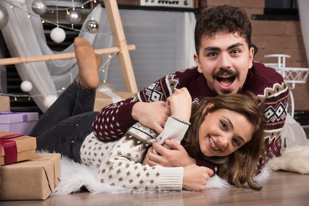 Young couple lying down on the floor in Christmas interior.