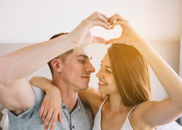 Young couple making heart shape from hands