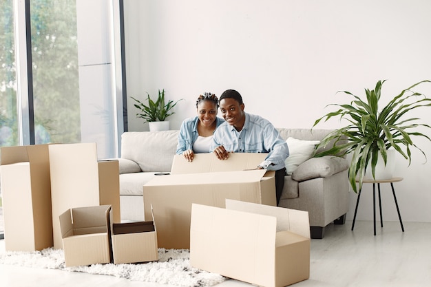 Free photo young couple moving in to new home together. african american couple with cardboard boxes.