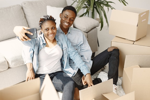 Free photo young couple moving in to new home together. african american couple with cardboard boxes.