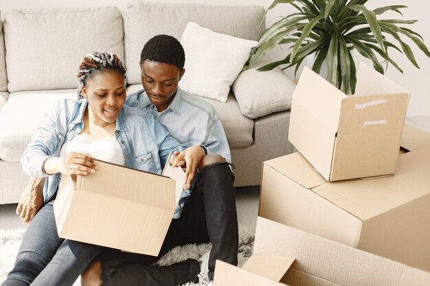 Young couple moving in to new home together. African american couple with cardboard boxes.