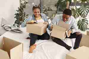 Free photo young couple moving in to new home together. african american couple with cardboard boxes.